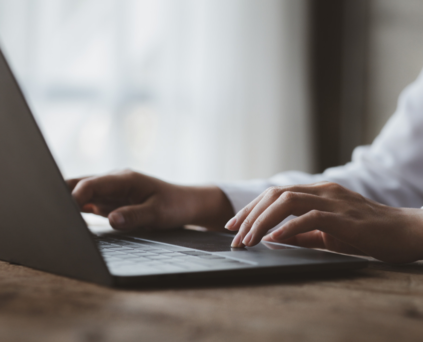 Side view of someone's hands typing on a laptop