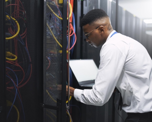 Tech professional working in data center with laptop
